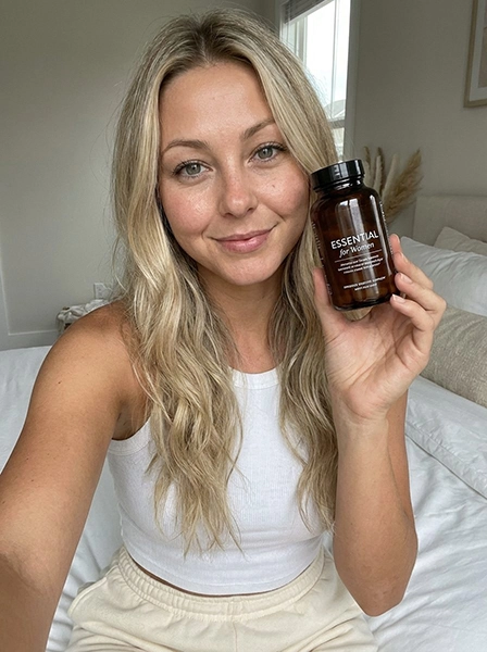 Woman holding a supplement bottle in a bright lifestyle portrait